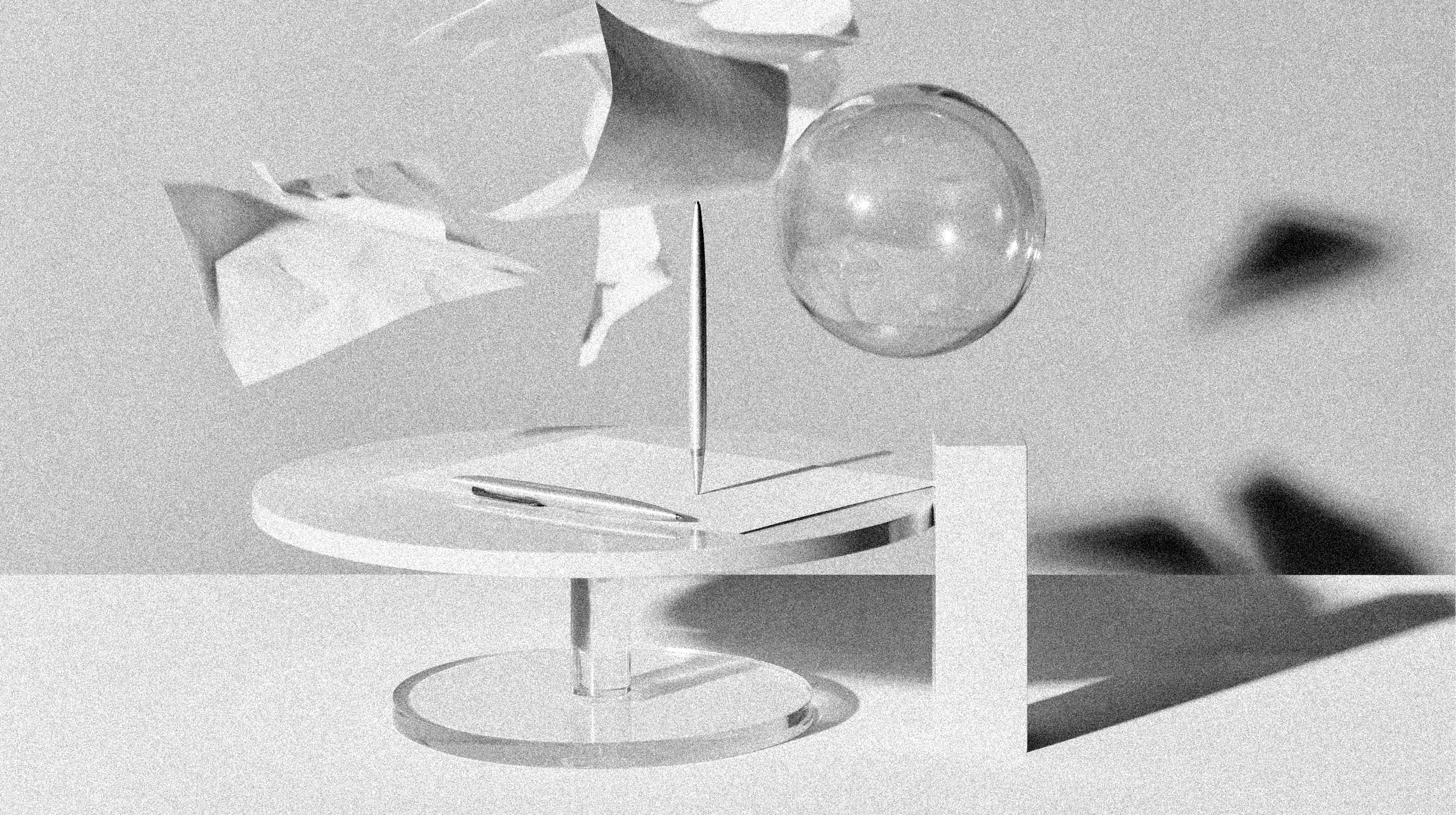 Still life — glass sphere, paper forms and an acrylic stand on a soft grey surface