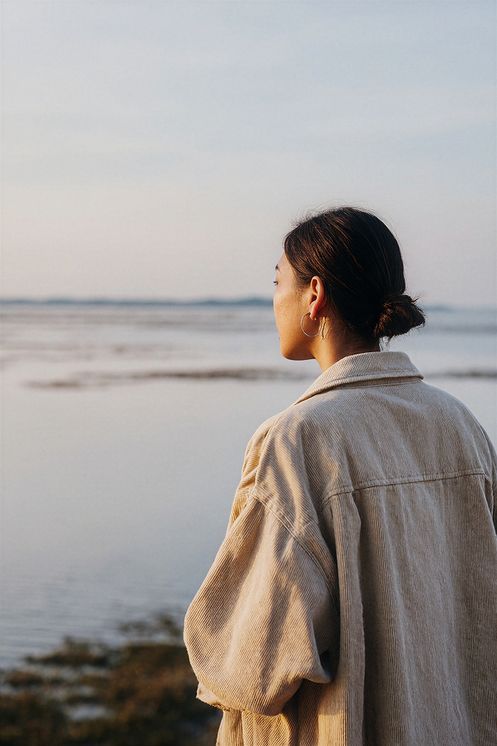 Portrait, woman in corduroy jacket by the sea at dusk