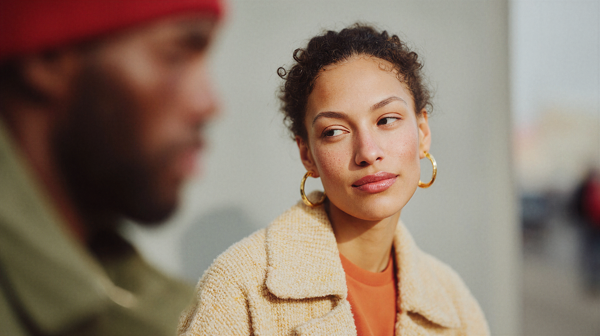 Woman with gold hoop earrings looking aside, soft outdoor light